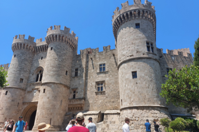Mächtiger Großmeisterpalast in Rhodos mit Rundtürmen und Steinmauern unter blauem Himmel – Wahrzeichen der Altstadt und Zeugnis der Rittergeschichte.