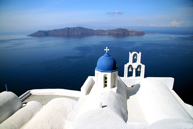 Santorini – weiße Kirche mit blauem Kuppeldach und Blick auf die Ägäis